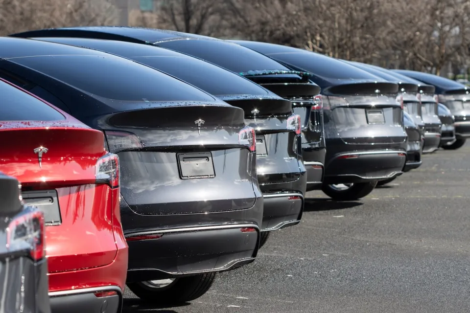 Low view of row of red, grey, and black Tesla electric cars.